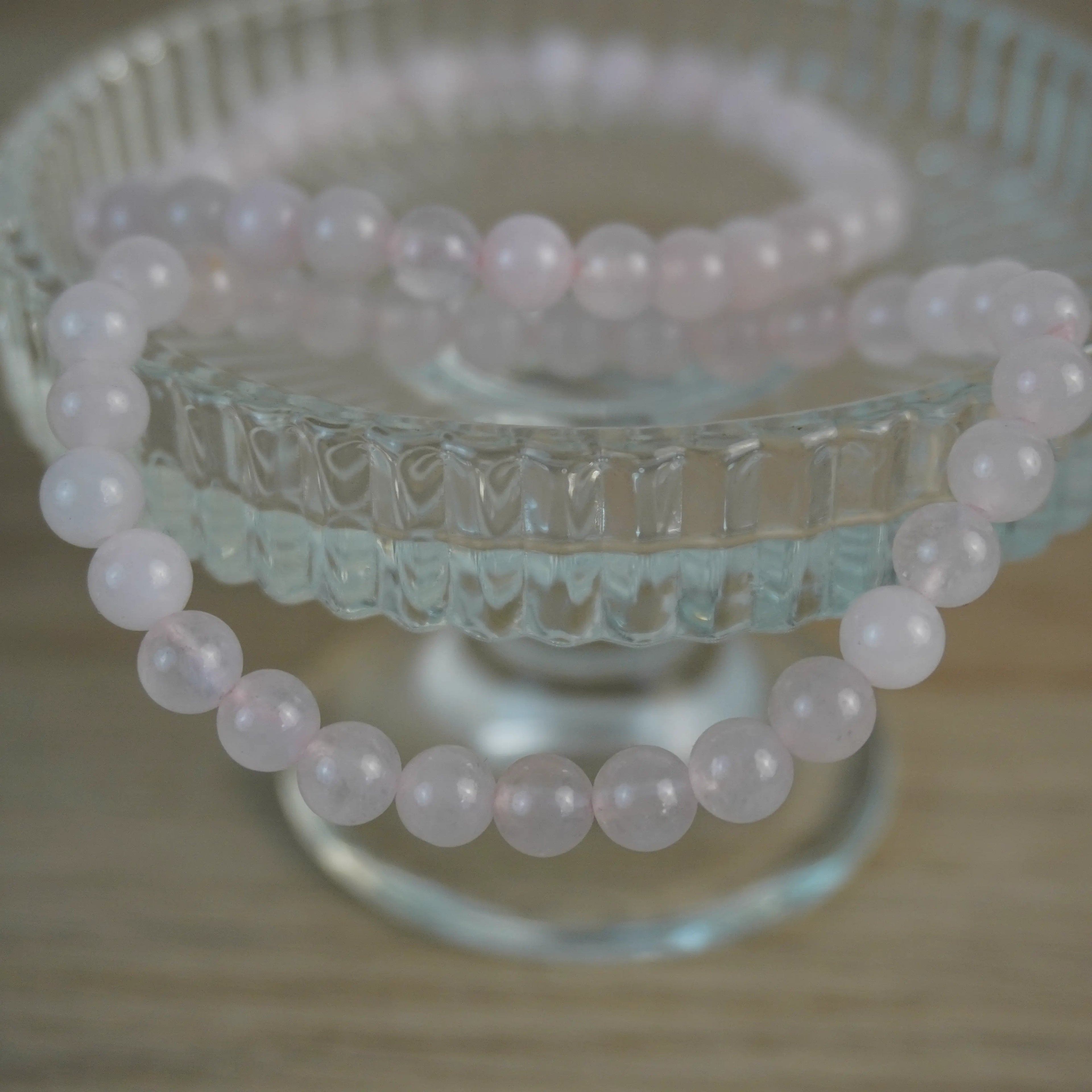 Rosenquarz Kugelarmband dekorativ auf Glasständer arrangiert