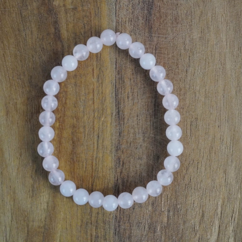Zartes Rosenquarz Kugelarmband auf Holz Oberfläche