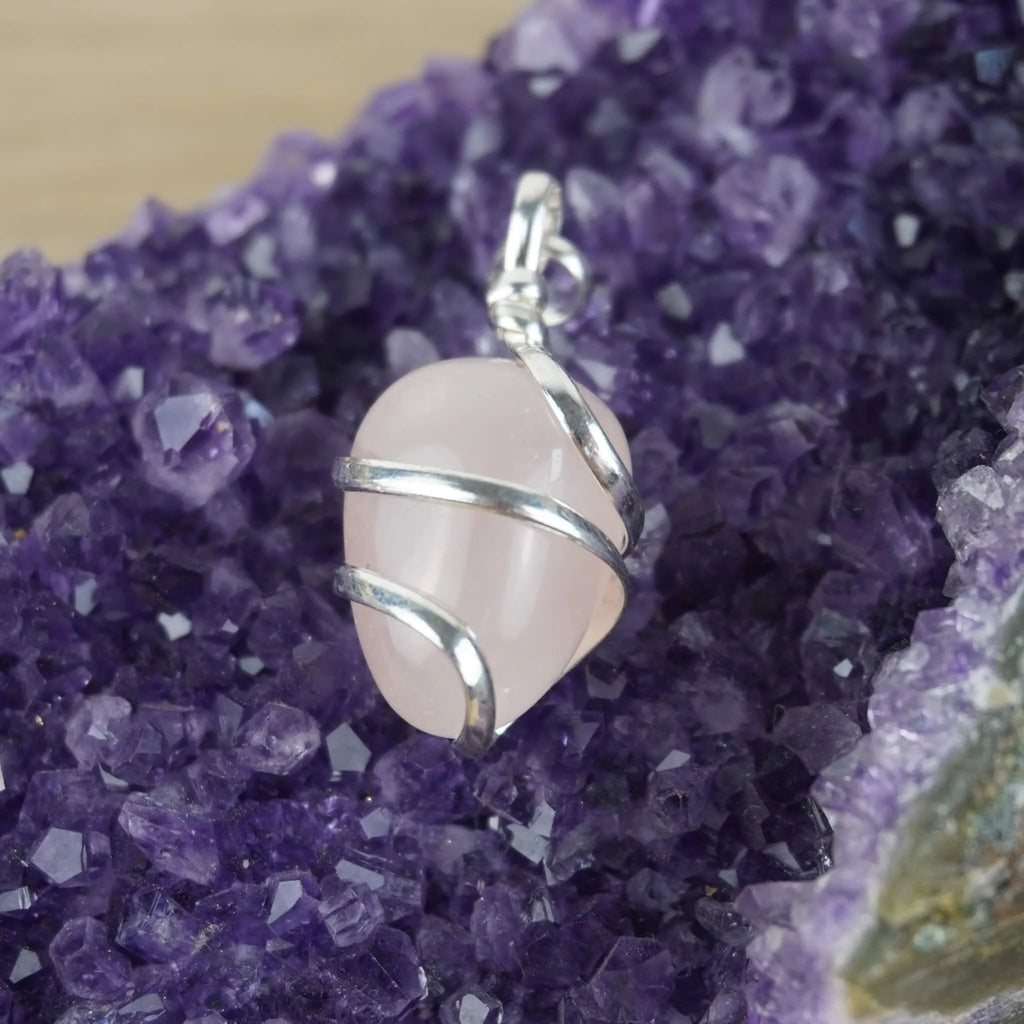Rosenquarz Kettenanhänger mit Silberfassung präsentiert auf violetter Amethyst-Druse