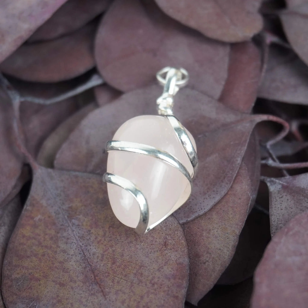 Rosenquarz Kettenanhänger mit silberner Spiralfassung auf lila Eukalyptusblättern