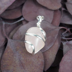 Rosenquarz Kettenanhänger mit silberner Spiralfassung auf lila Eukalyptusblättern