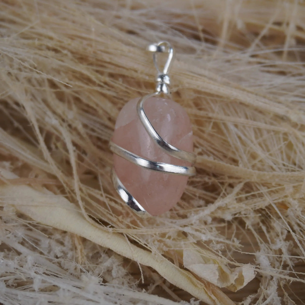 Rosenquarz Kettenanhänger mit Silberfassung dekoriert auf hellen Naturfasern