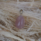 Rosenquarz Kettenanhänger mit silberner Öse auf hellen Naturfasern dekoriert