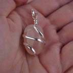 Rosenquarz Kettenanhänger mit Silberfassung in einer Hand liegend