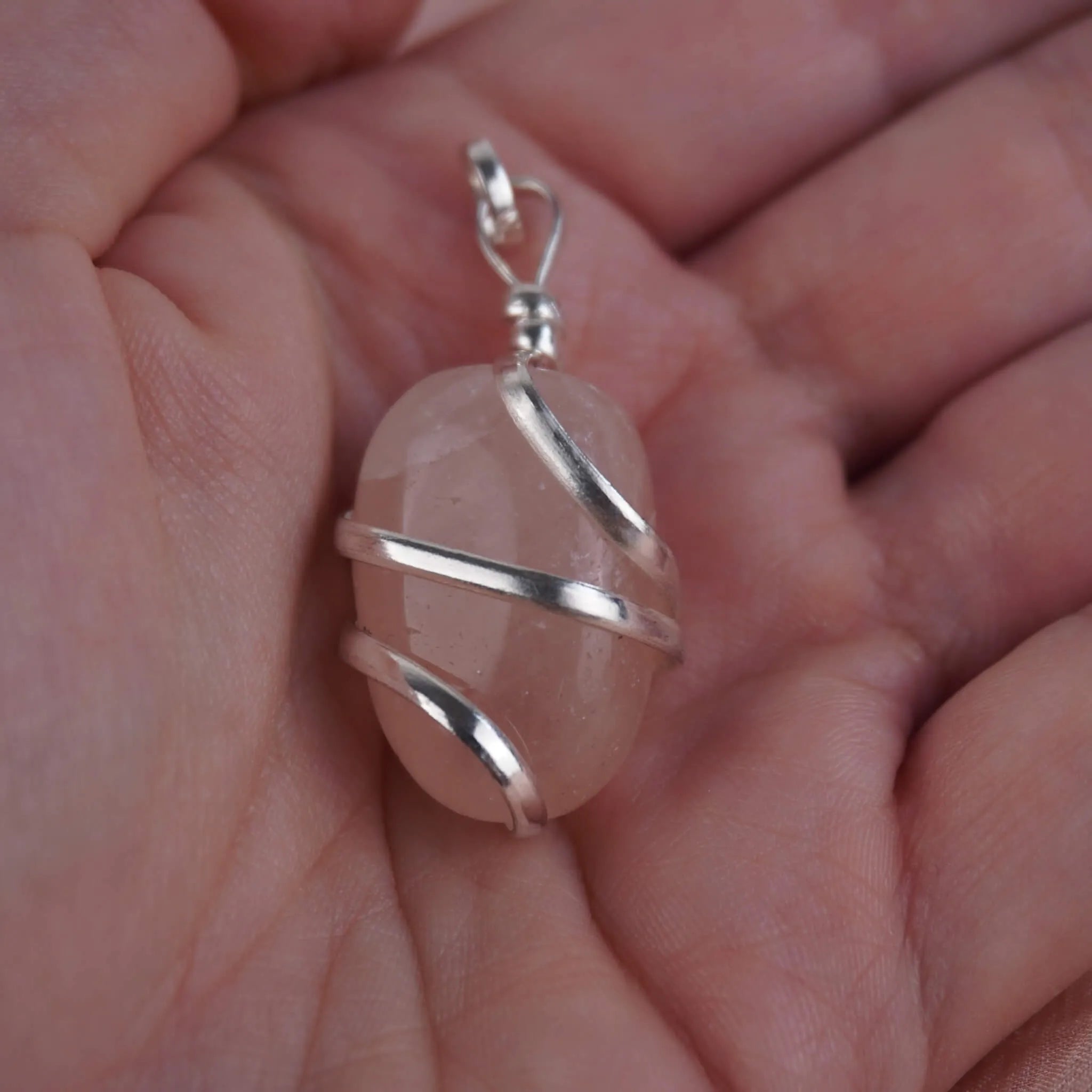 Rosenquarz Kettenanhänger mit Silberfassung in einer Hand liegend