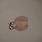 Zartrosa Rosenquarz Trommelstein Kettenanhänger mit silberfarbener Öse auf glänzender Fläche