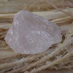 Rosenquarz Rohstein liegt auf hellem Naturmaterial