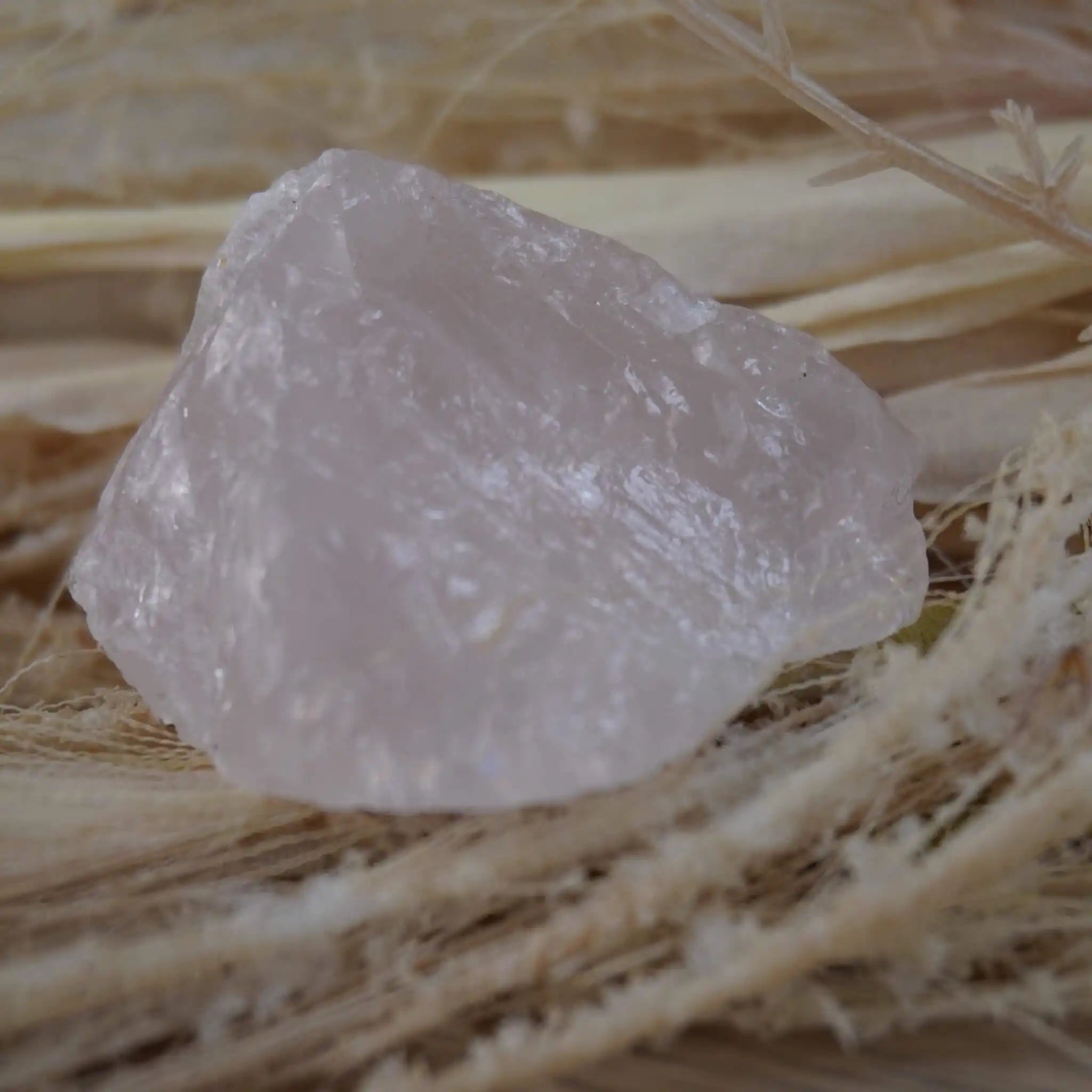 Rosenquarz Rohstein liegt auf hellem Naturmaterial