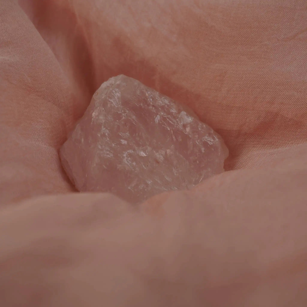 Rosenquarz Rohstein auf rosa Seidentuch