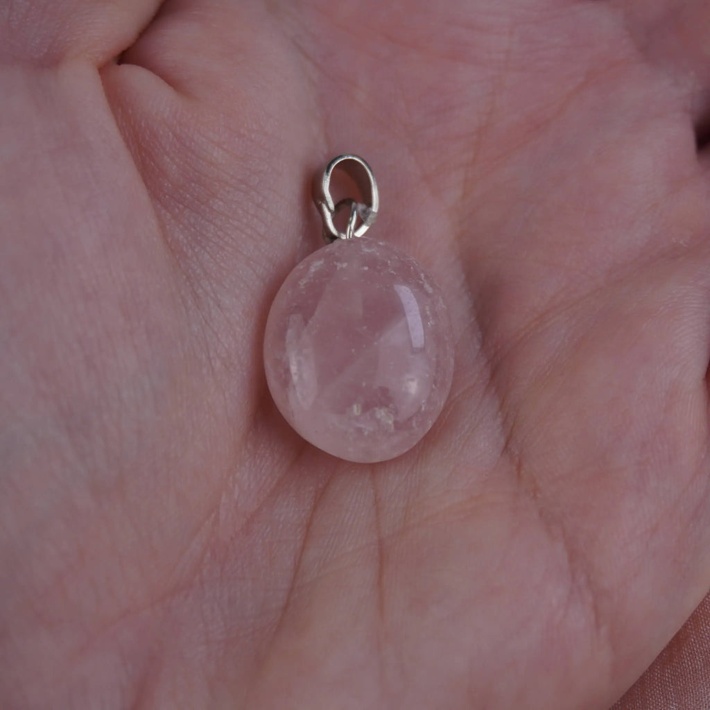 Rosenquarz Kettenanhänger mit silberfarbener Öse in einer Hand liegend
