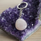 Rosenquarz Trommelstein Schlüsselanhänger auf Amethyst-Kristallen