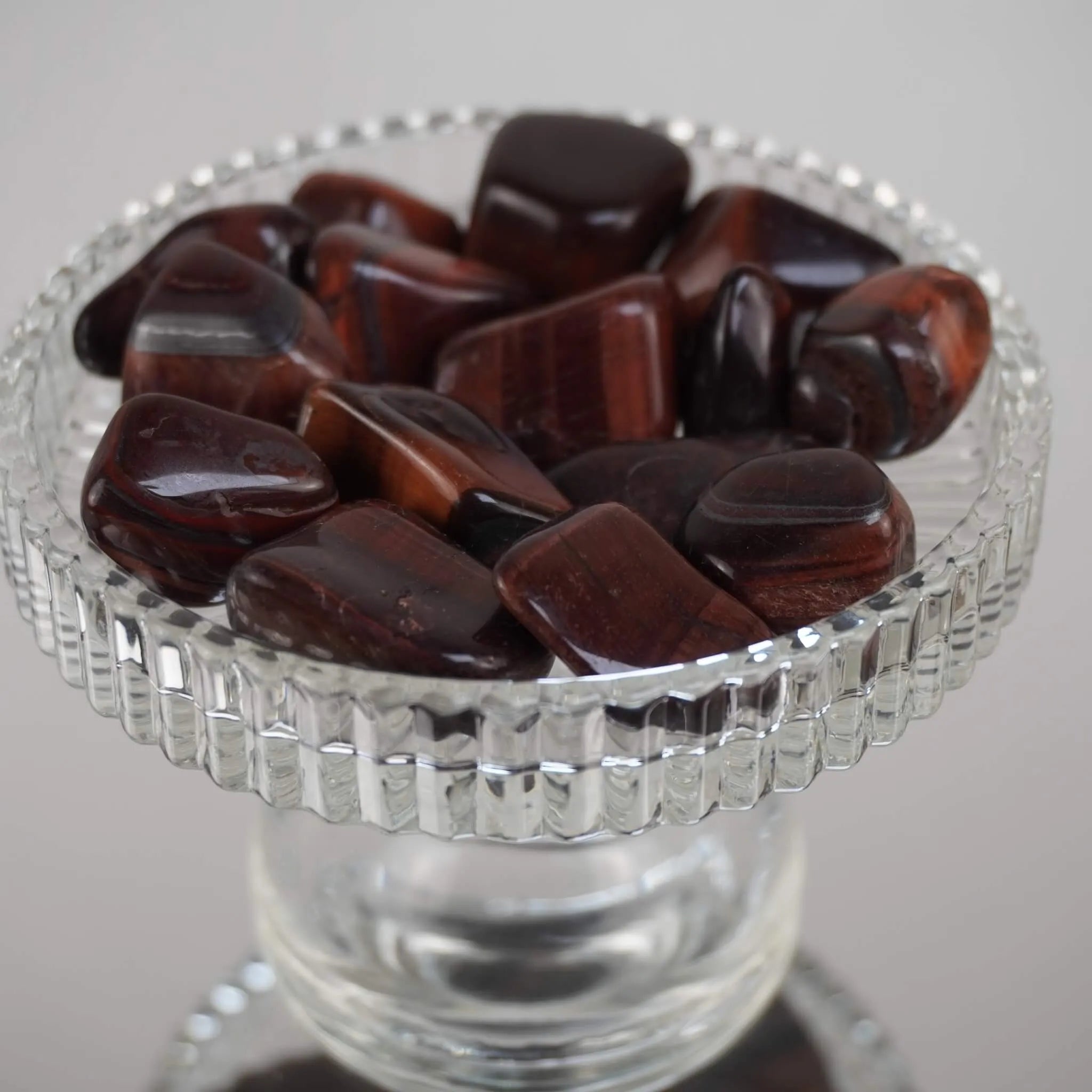 Mehrere rote Tigerauge Trommelsteine mit satten Rottönen in einem Glaskelch