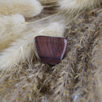 Roter Tigerauge Trommelstein arrangiert auf beigen Ziergräsern