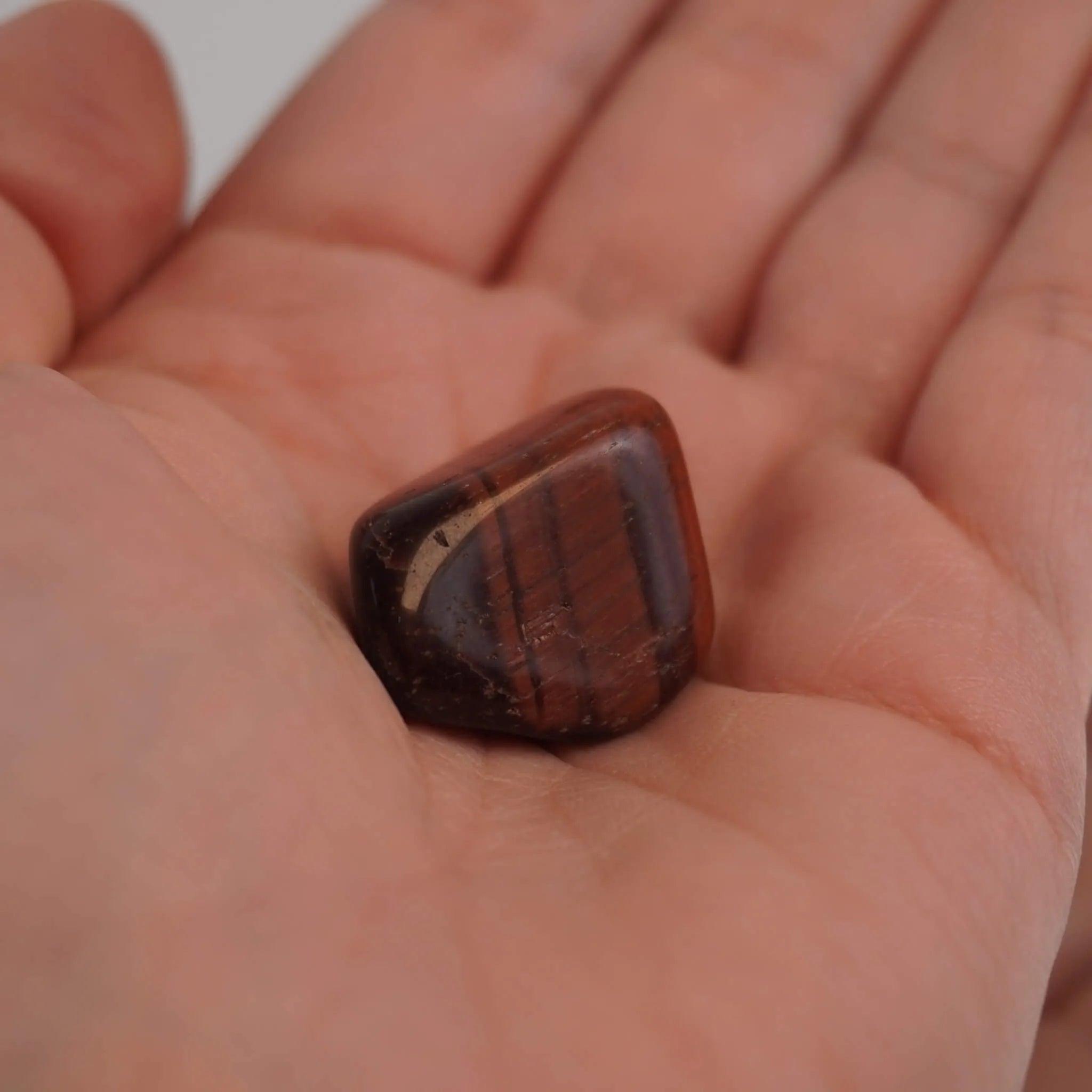 Roter Tigerauge Trommelstein mit Maserung in einer geöffneten Hand