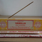 Satya Vanilla Räucherstäbchen Packung mit angezündetem Räucherstäbchen im Vordergrund