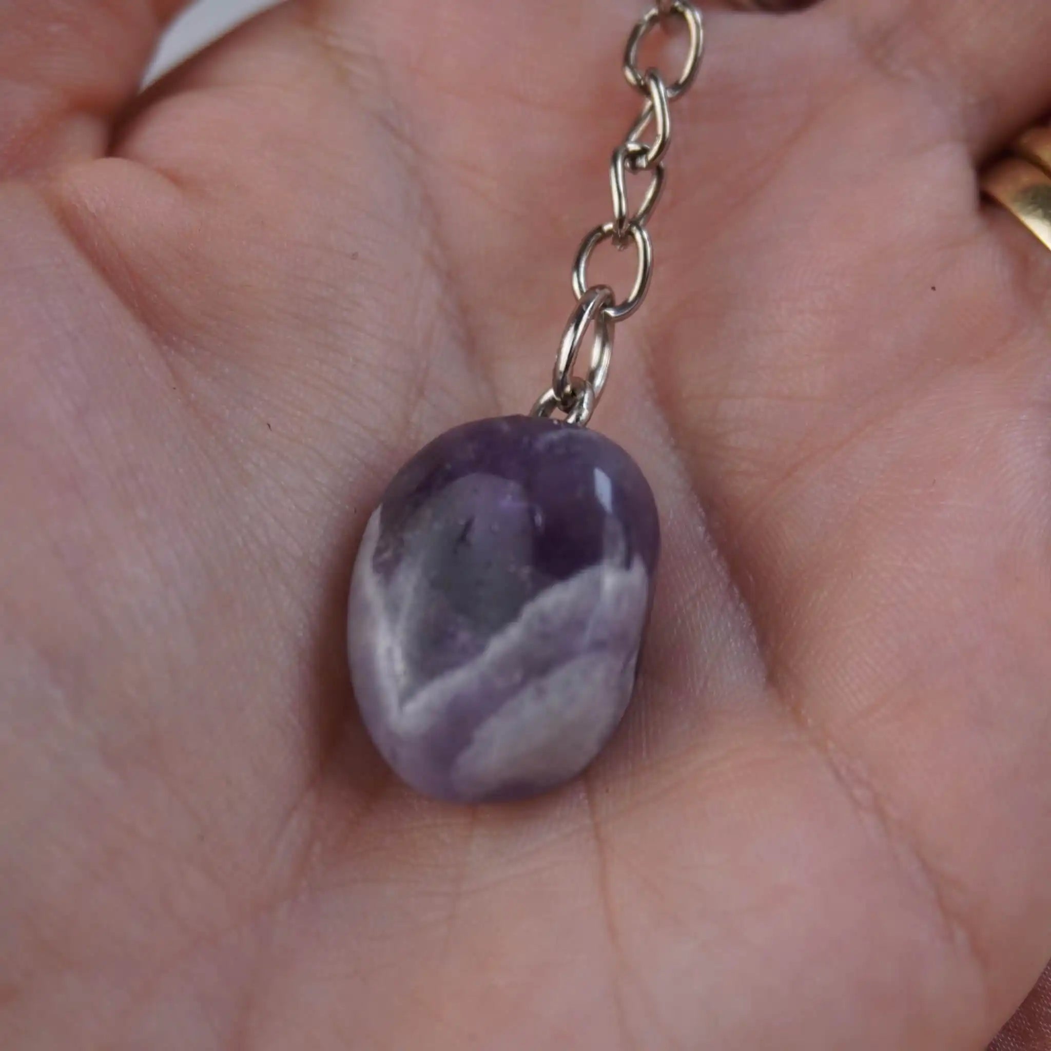 Schlüsselanhänger mit Amethyst Trommelstein in einer Hand gehalten