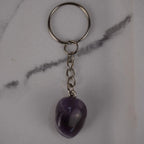 Amethyst Trommelstein Schlüsselanhänger auf hellem Marmor Hintergrund