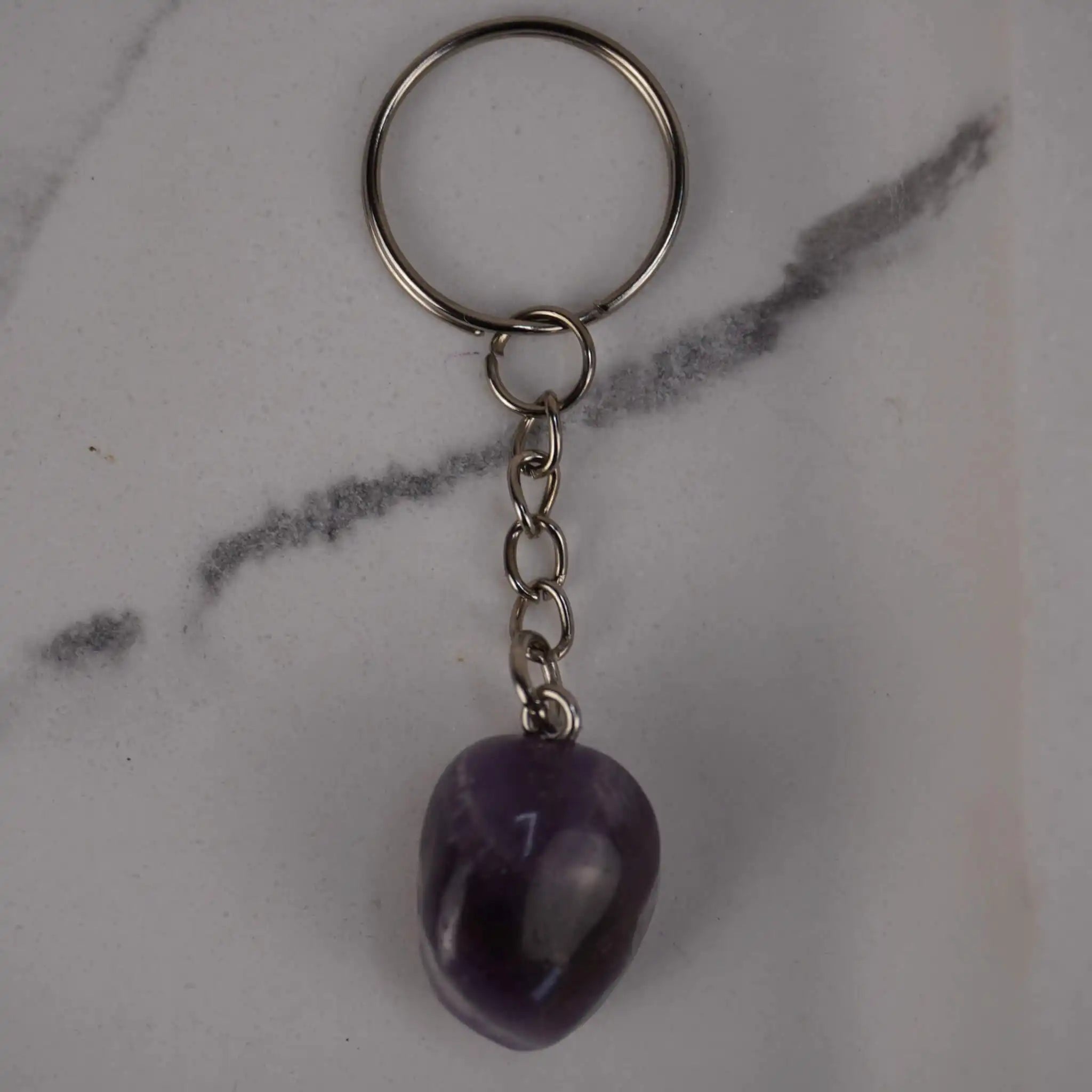 Amethyst Trommelstein Schlüsselanhänger auf hellem Marmor Hintergrund