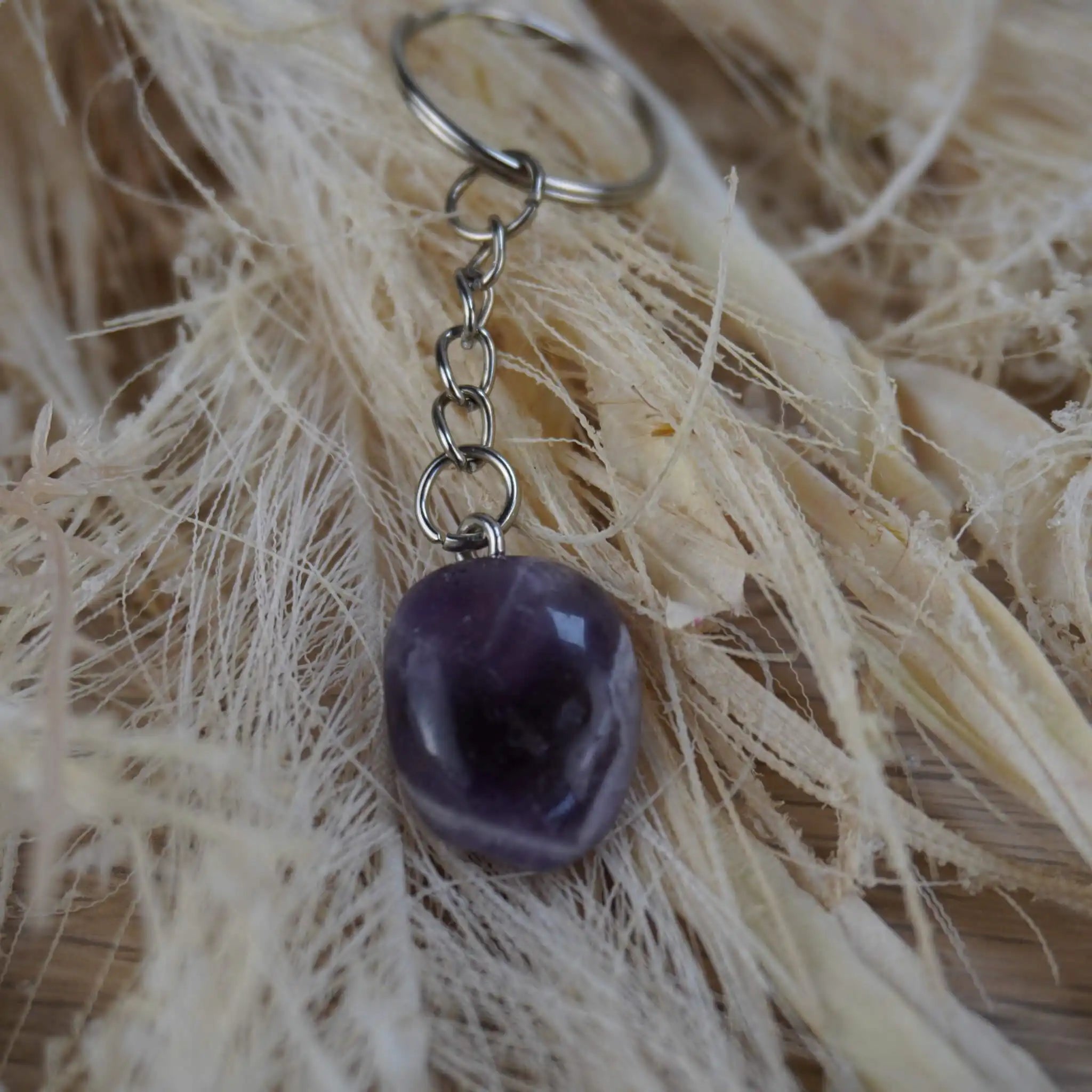 Amethyst Trommelstein Schlüsselanhänger auf Naturfaser-Hintergrund