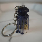 Protection Spell Jar Schlüsselanhänger mit dunklem Wachs und Kristallen, auf weißer Fläche