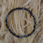 Schneeflocken Obsidian Kugelarmband auf hellem Naturfaserdekor mit sichtbarer Struktur