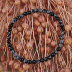 Schneeflocken Obsidian Kugelarmband vor rosafarbenen Trockenblumen mit Kontrast