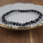 Schneeflocken Obsidian Kugelarmband auf weißem Teller mit feinem Goldrand