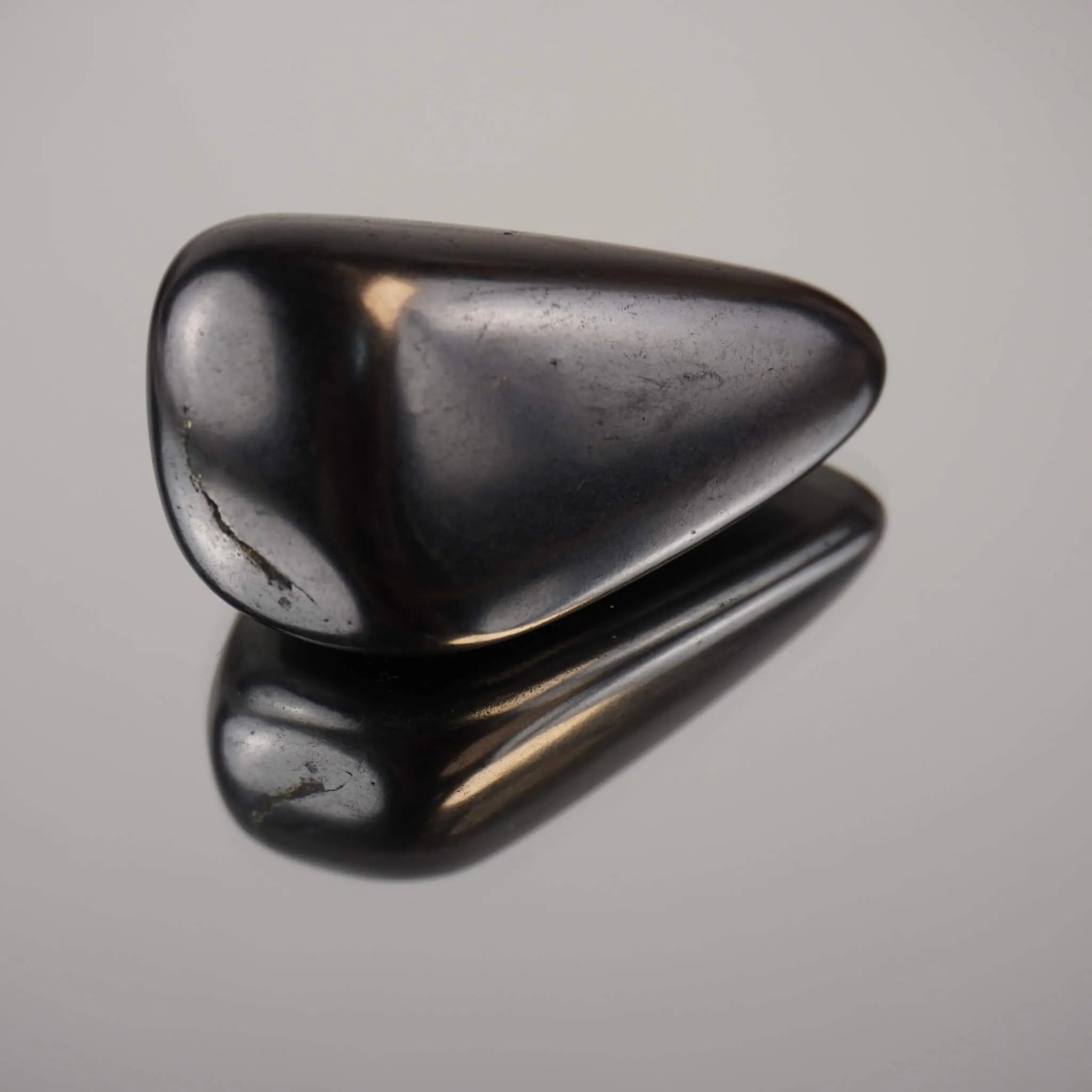 Schungit Trommelstein mit glänzender Oberfläche und klarer Spiegelung