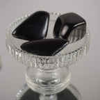 Drei dunkle Schungit Trommelsteine dekorativ auf klarem Glaskelch arrangiert