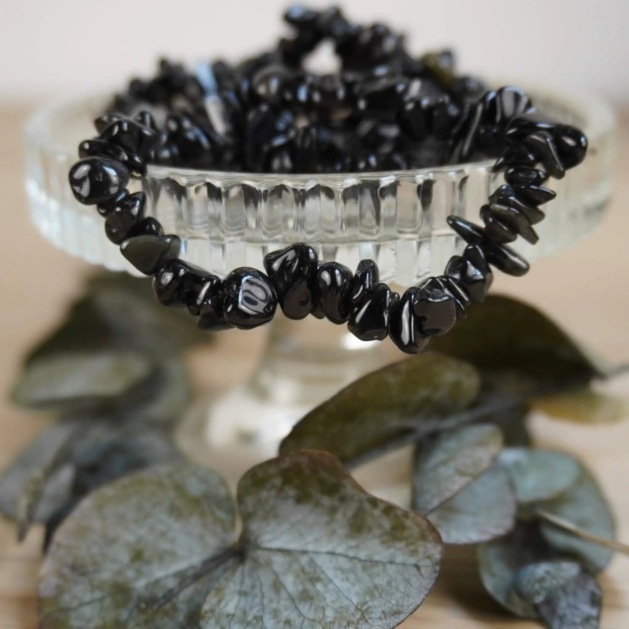 Schwarzer Achat Splitterarmband auf Glas-Schale und Eukalyptusblättern