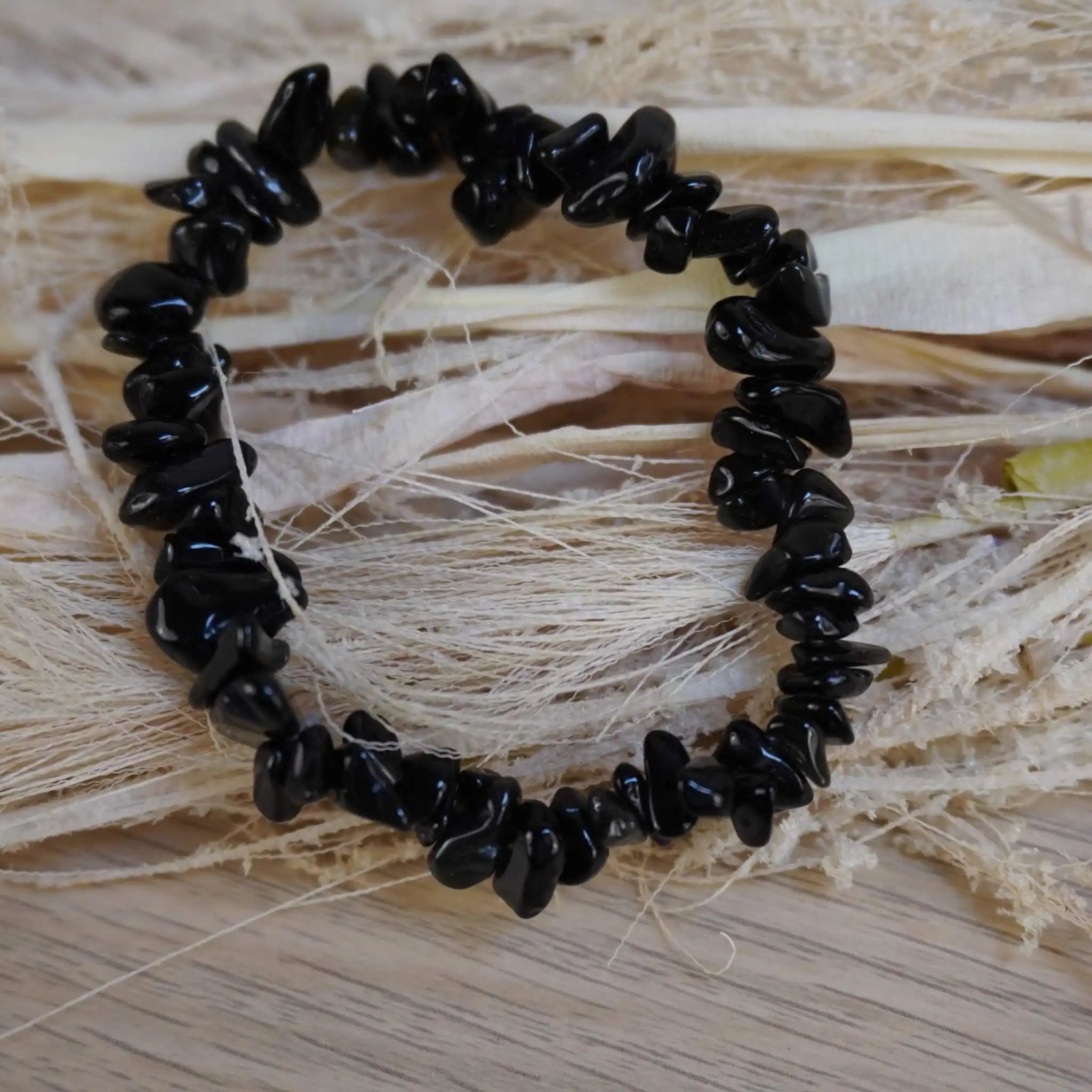 Schwarzer Achat Splitterarmband auf hellem Holz und Naturfasern