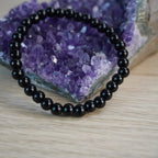 Schwarzer Turmalin Kugelarmband vor Amethyst-Kristall Dekoration