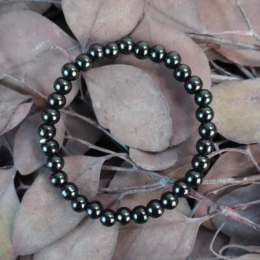 Schwarzer Turmalin Kugelarmband auf braunen Blättern