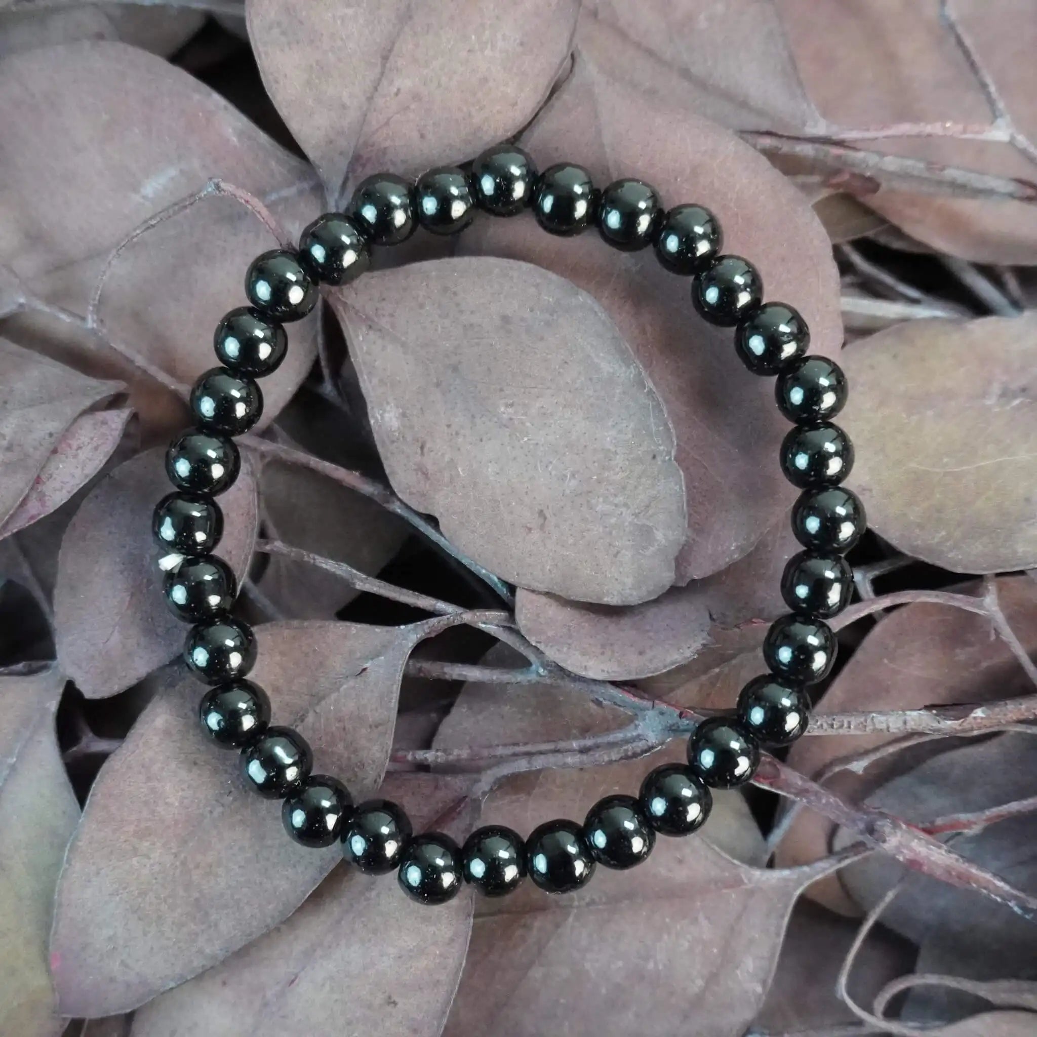 Schwarzer Turmalin Kugelarmband auf braunen Blättern