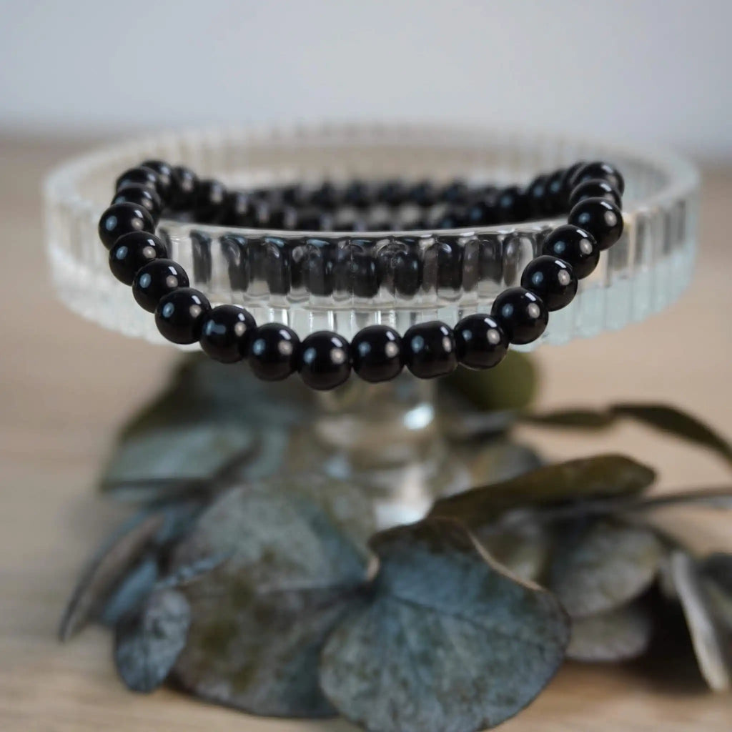 Schwarzer Turmalin Kugelarmband auf Kristallschale