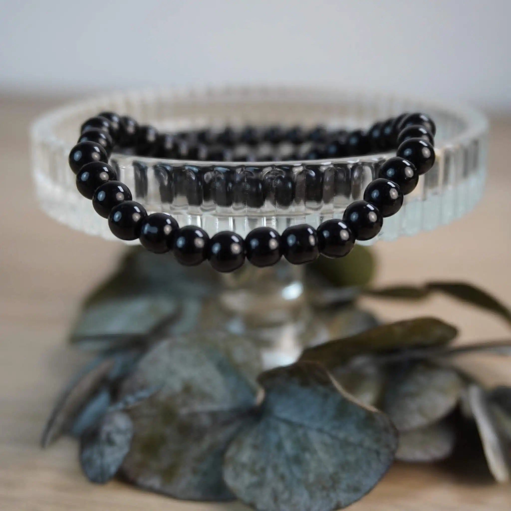 Schwarzer Turmalin Kugelarmband auf Kristallschale