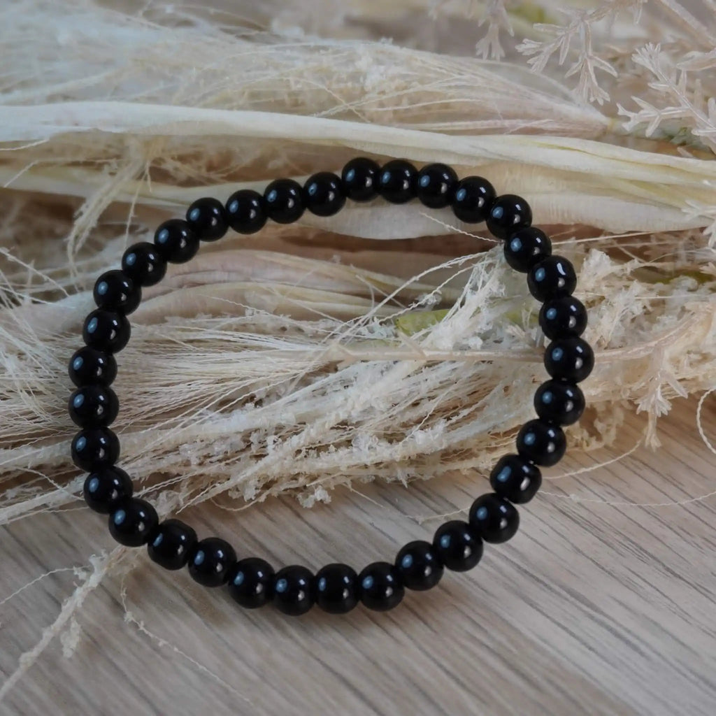 Schwarzer Turmalin Kugelarmband auf hellem Naturstroh