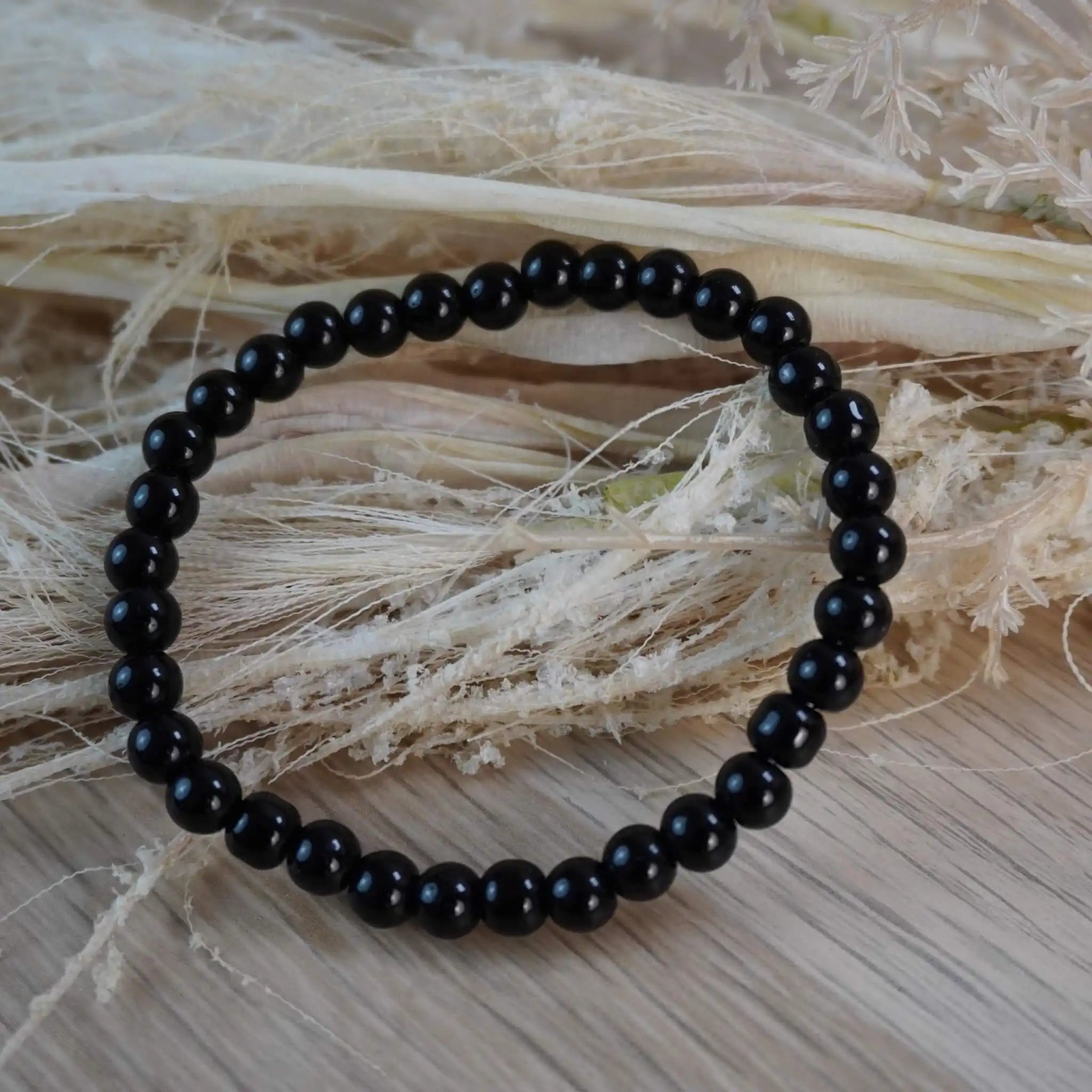 Schwarzer Turmalin Kugelarmband auf hellem Naturstroh