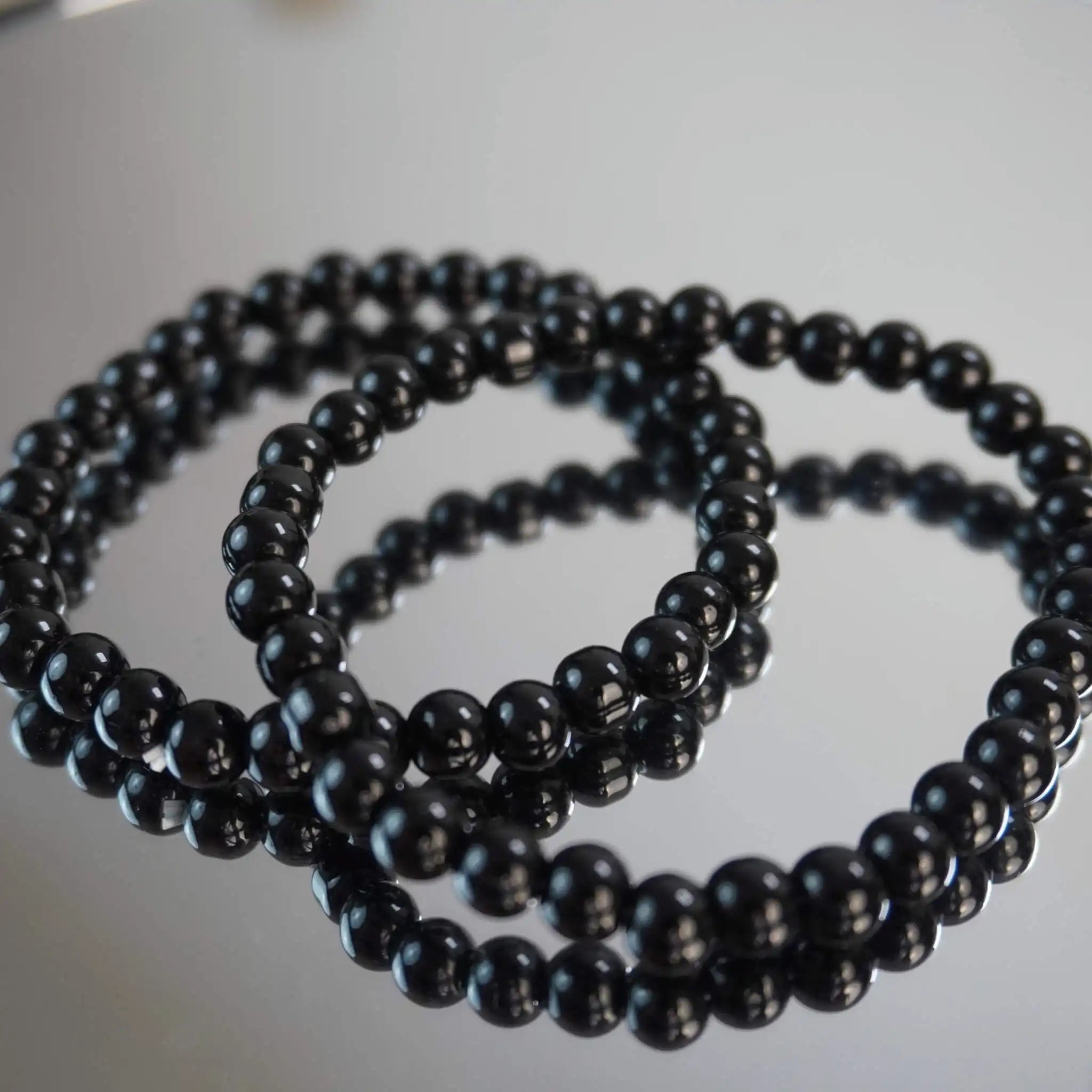 Schwarzer Turmalin Kugelarmband auf Spiegeloberfläche