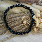 Schwarzer Turmalin Kugelarmband auf Trockenblumen und Gräsern