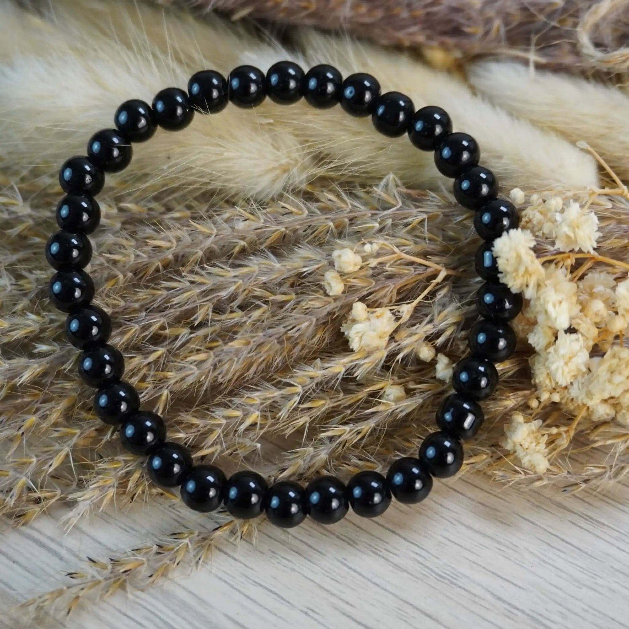 Schwarzer Turmalin Kugelarmband auf Trockenblumen und Gräsern