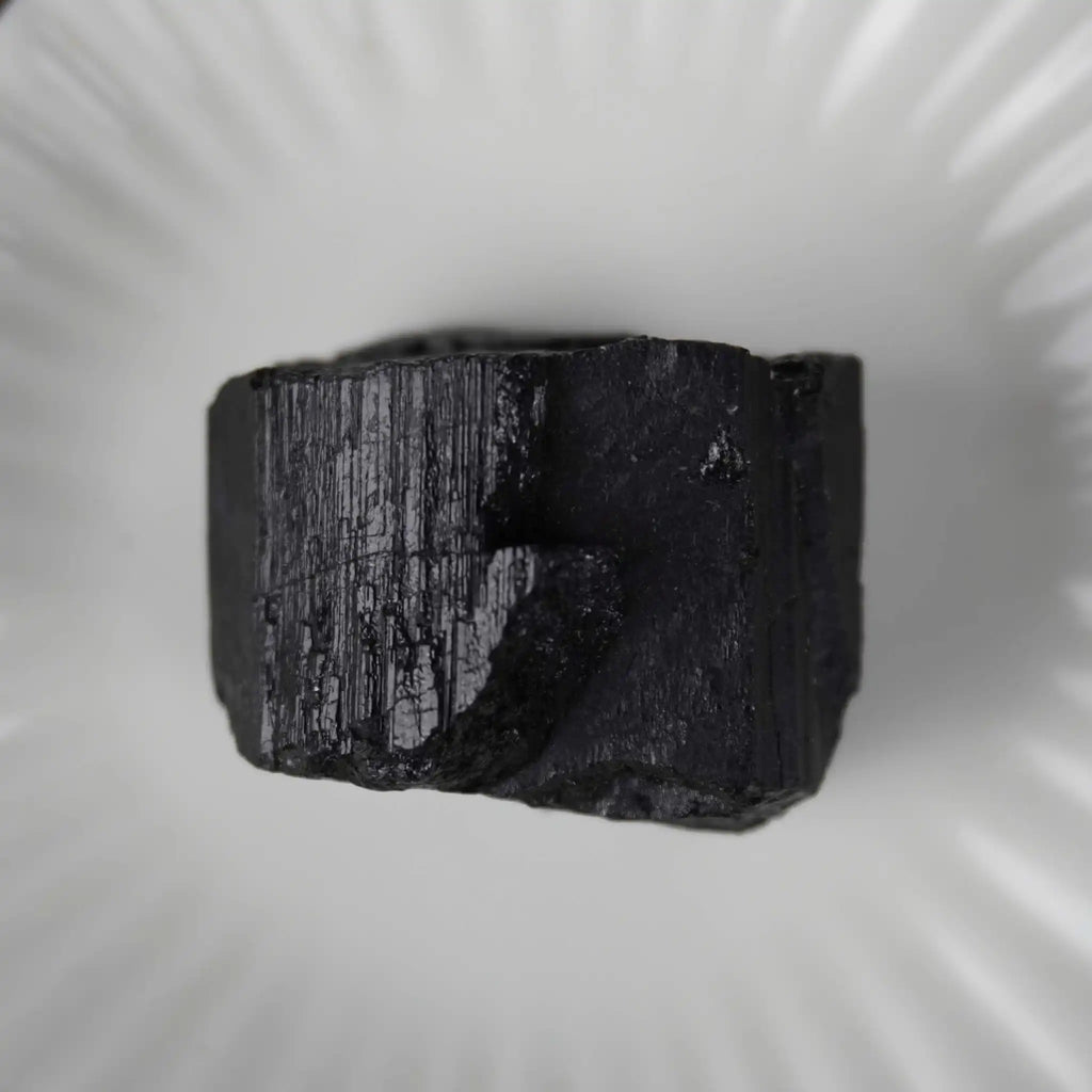 Schwarzer Turmalin Rohstein in einer weißen Schale präsentiert