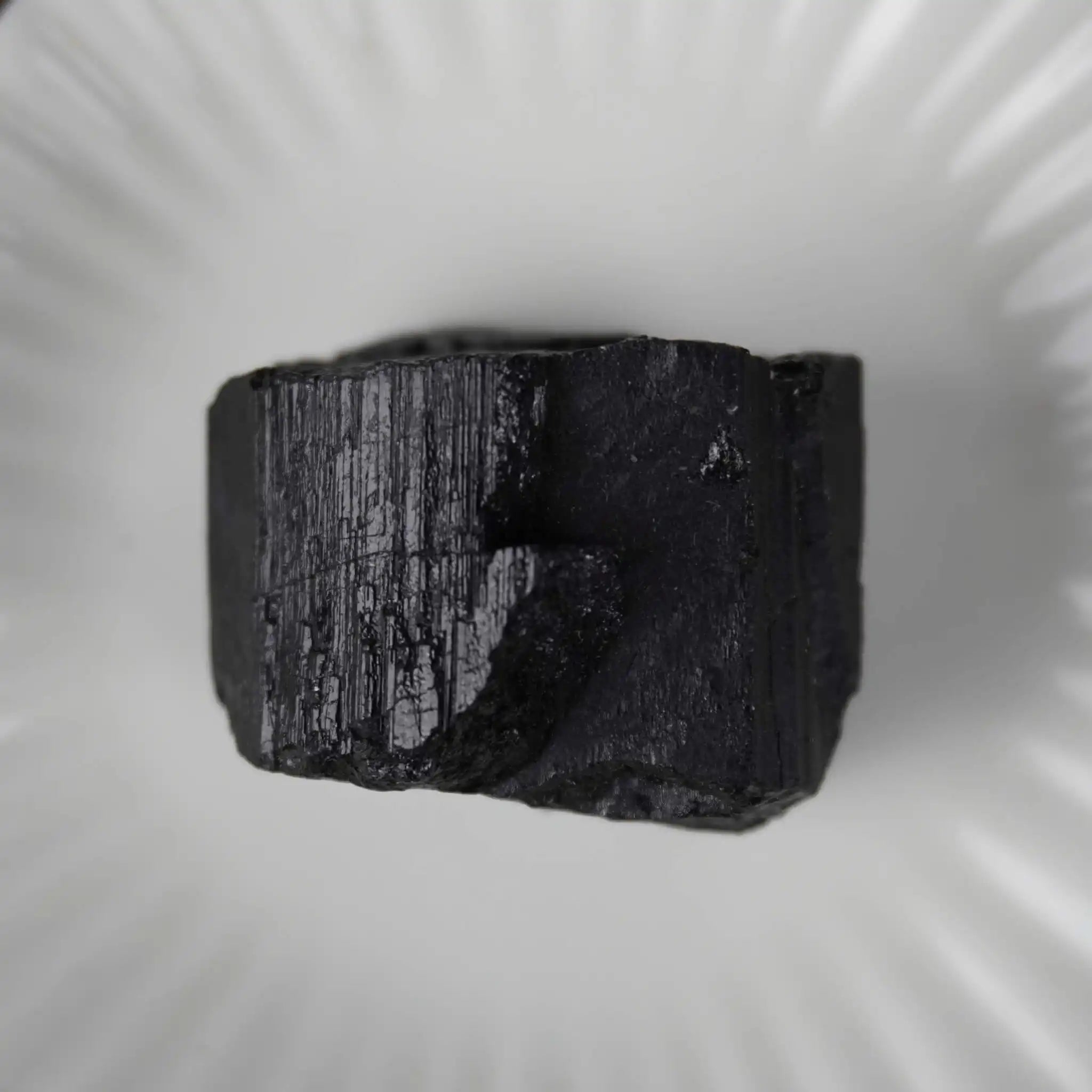 Schwarzer Turmalin Rohstein in einer weißen Schale präsentiert