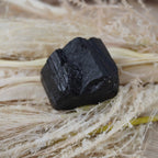 Schwarzer Turmalin Rohstein auf hellem Naturmaterial dekoriert