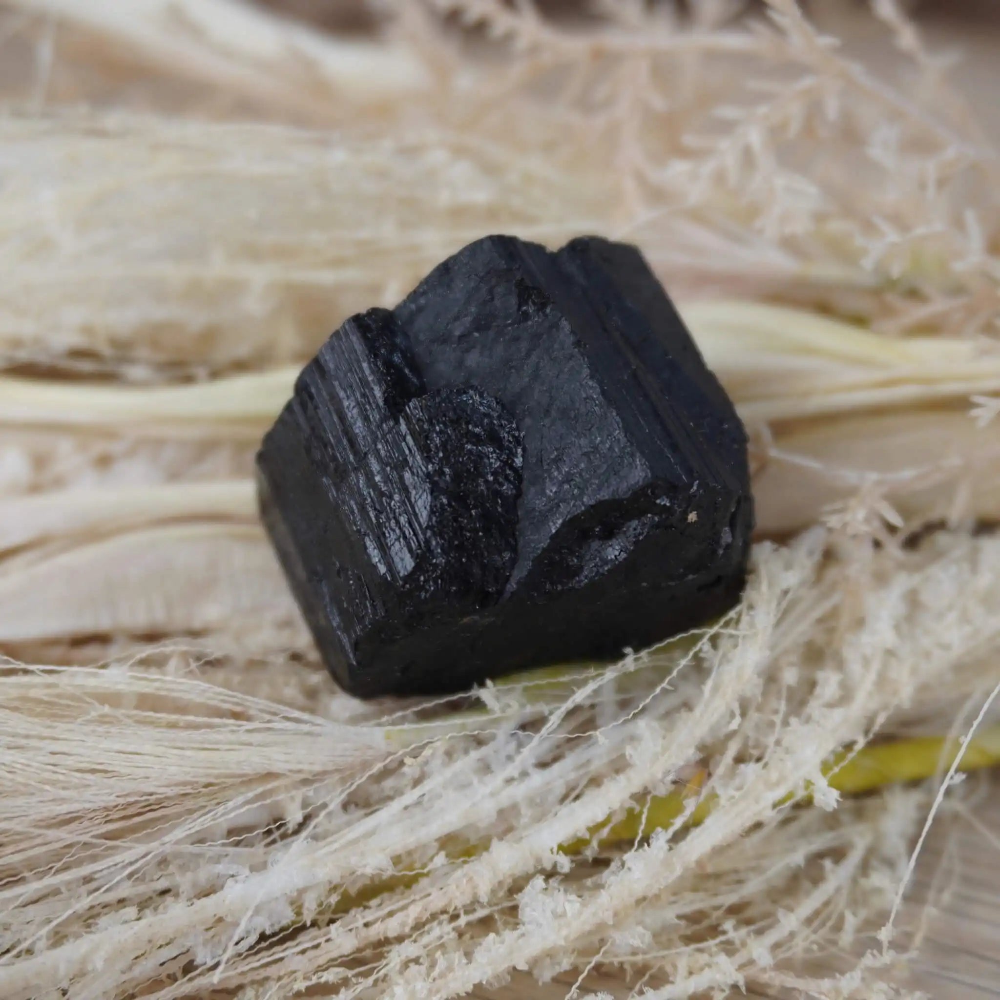 Schwarzer Turmalin Rohstein auf hellem Naturmaterial dekoriert