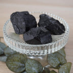 Drei schwarze Turmalin Rohsteine in einer Glaskristallschale