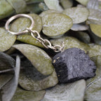 Schwarzer Turmalin Schlüsselanhänger auf grünen Eukalyptusblättern