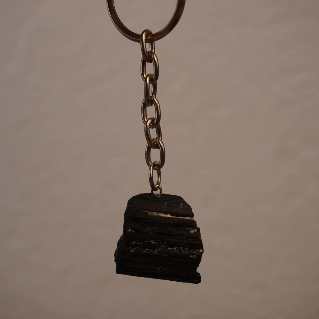 Schwarzer Turmalin Schlüsselanhänger frei hängend vor neutralem Hintergrund