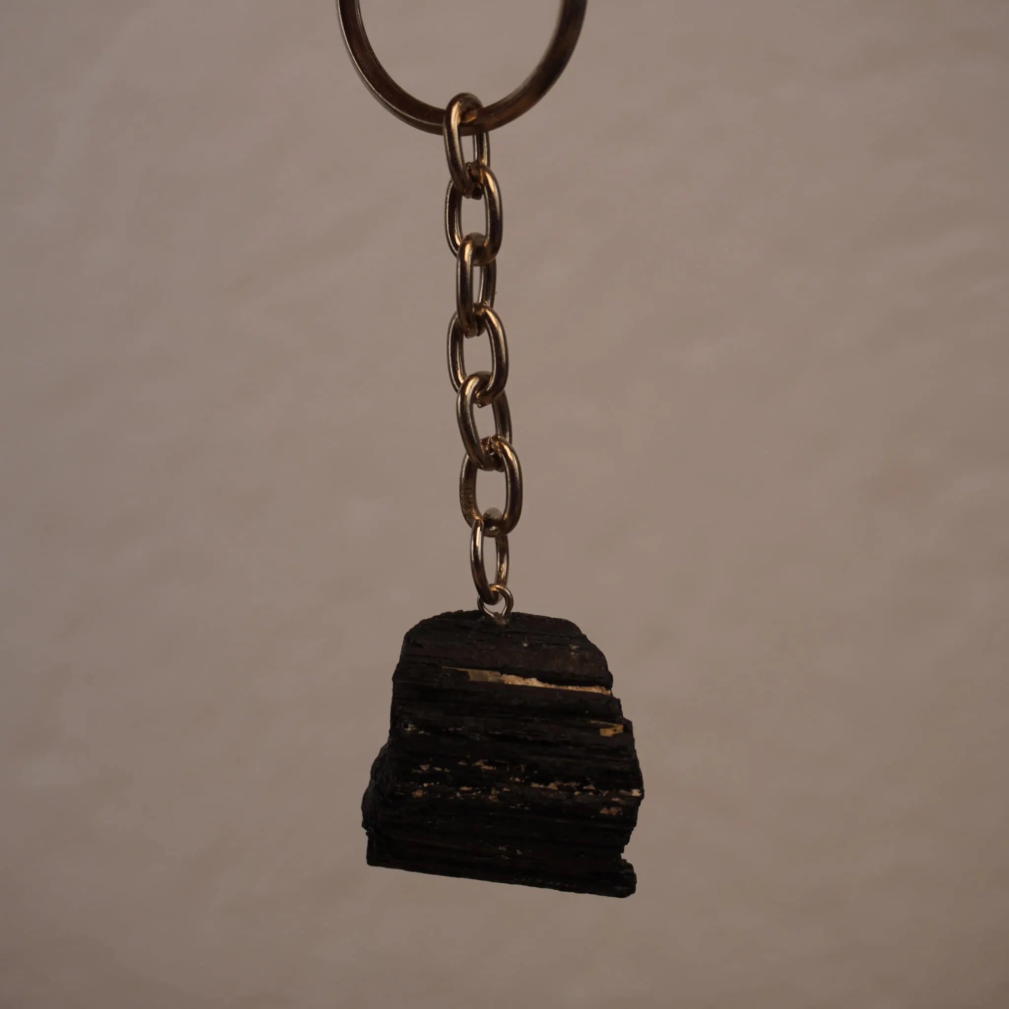 Schwarzer Turmalin Schlüsselanhänger frei hängend vor neutralem Hintergrund