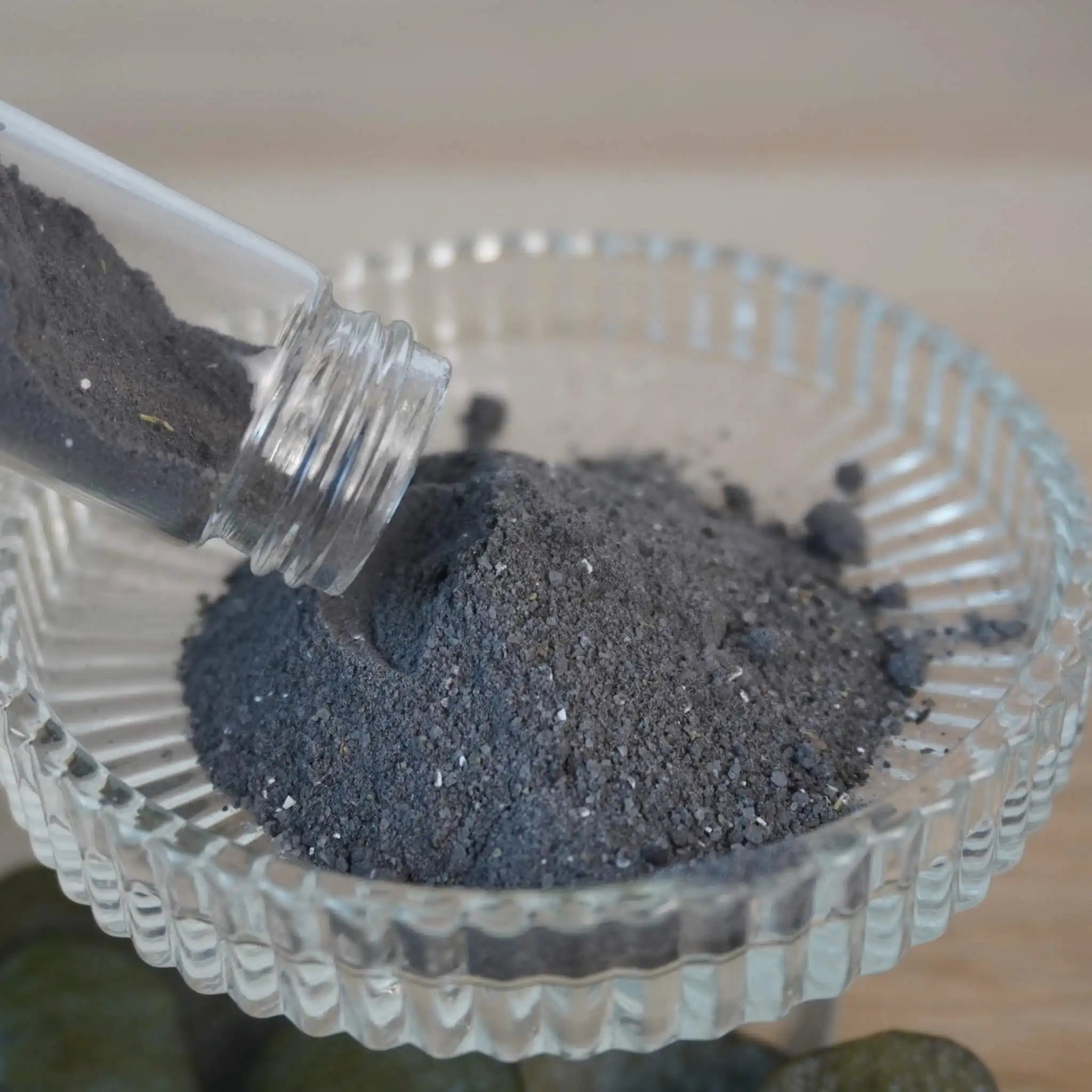 Schwarzes Dekosalz wird aus Glasröhre in eine Schale geschüttet